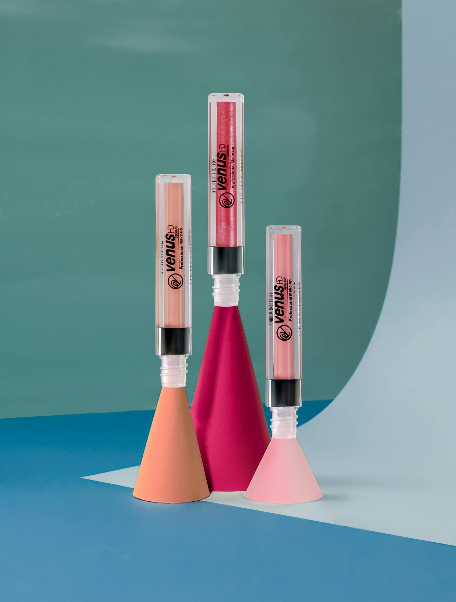 Stylish lip gloss tubes displayed on modern geometric shapes, perfect for beauty and fashion themes.